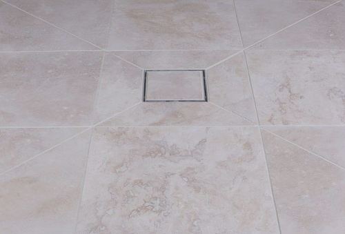 Example of tiling up to a square wet room floor drain showing mitre cuts in tiling