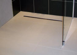 Picture showing linear Flo Dec finished installation with tiled floor and frameless glass shower screen
